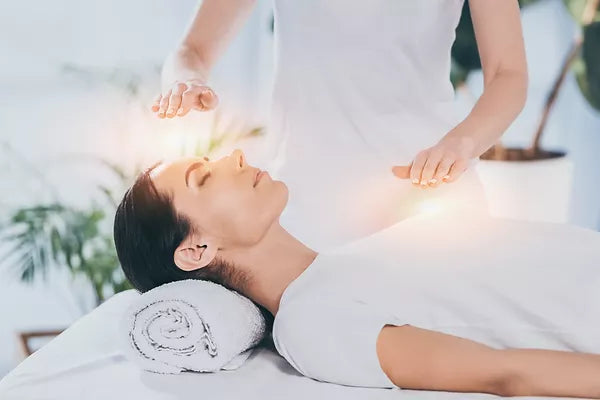 side_view_of_calm_young_woman_receiving_reiki_healing_therapy_on_head_and_chest.webp